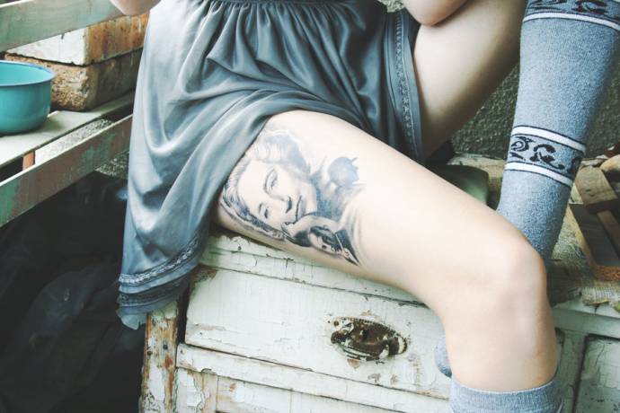 Татуировка Агата Кристи на бедре девушки