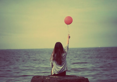 Девушка с красным шариком смотрит на море