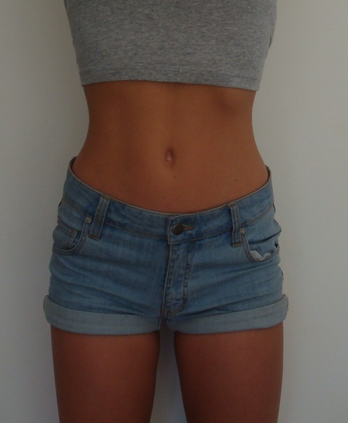 Плоский живот девушки в джинсовых шортах