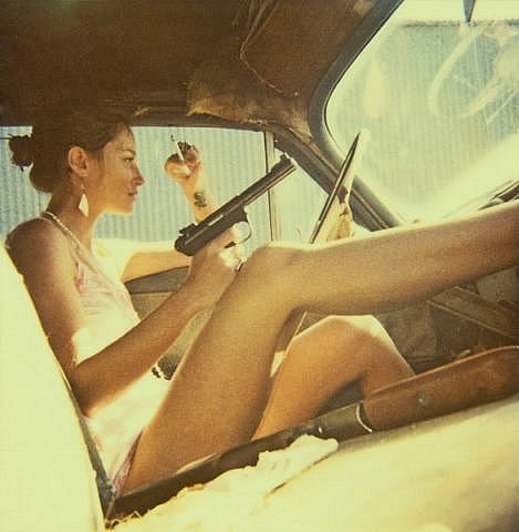 крутая девушка с оружием и сигаретой в автомобиле