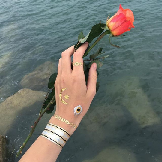 Роза в руке на водой и серебристые тату