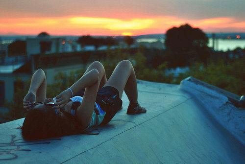 Девушка в сумерках лежит на крыше дома