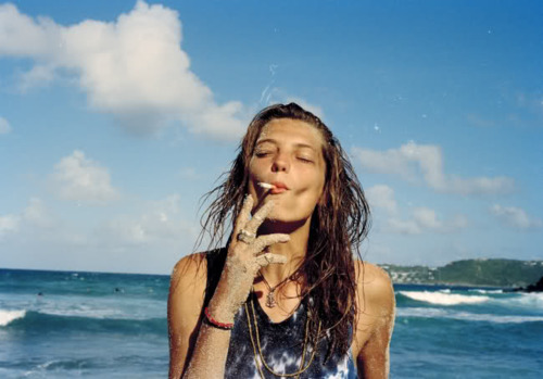 Девушка у моря затягивается сигаретой