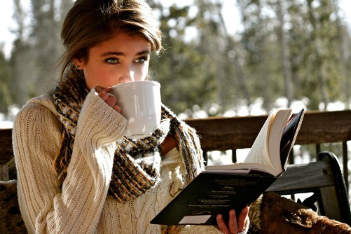 Девушка на веранде пьет чай и читает книгу