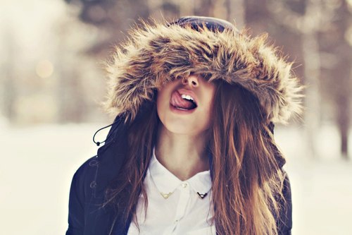 Девушка в куртке с капюшоном с высунутым языком