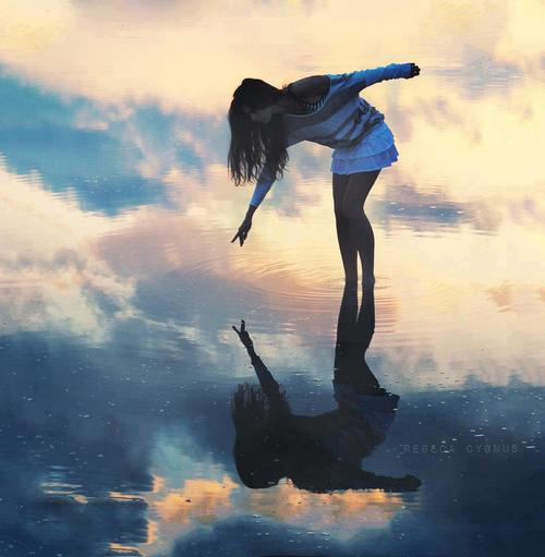 Девушка стоит в воде, где отражаеются облака