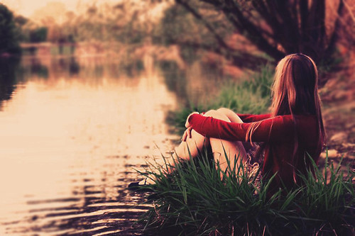 Одинокая девушка сидит у реки