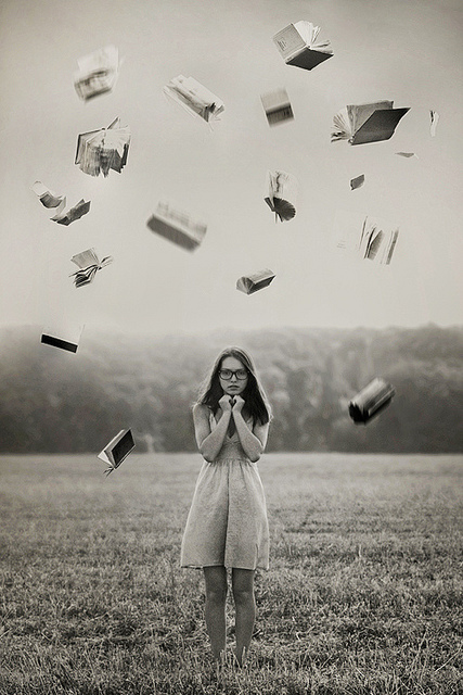 Девушка в очках, разбросавшая в поле книги