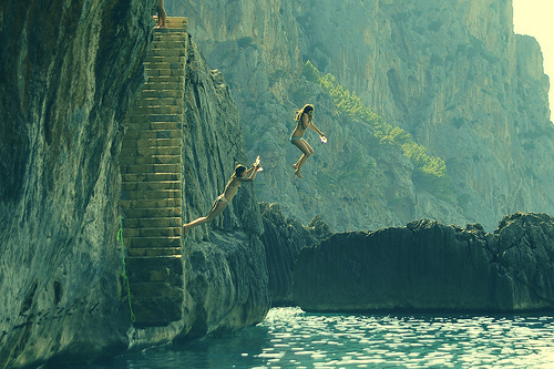 Прыгающие со скалы в воду две девушки