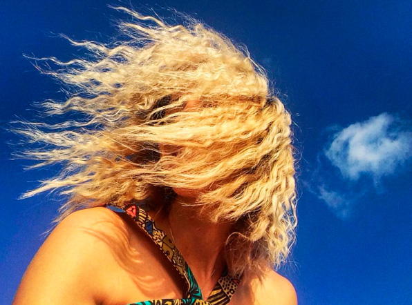 Блондинка с развевающимися волосами на фоне неба