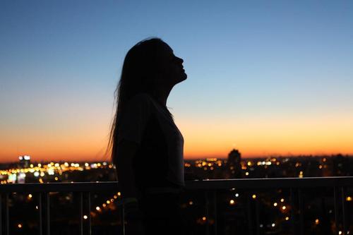 Силуэт девушки на крыше на фоне ночного города