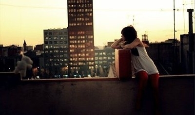 Девушка с чемоданом смотрит вдаль на крыше