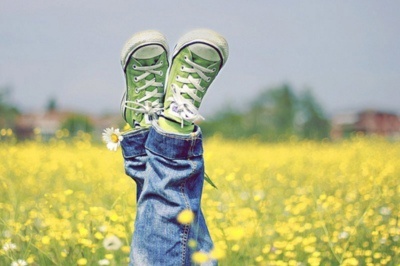 Ноги в джинсах и зеленых кедах на желтой поляне