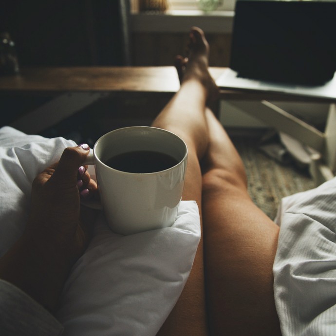 Девушка с чашкой кофе на постели