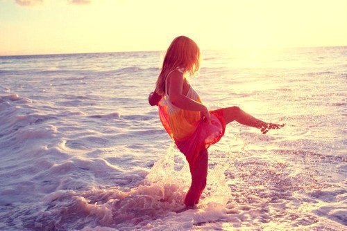 Девушка в лучах солнца плескается на море