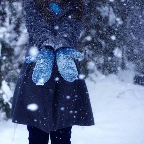 Девушка в варежках ловит снег