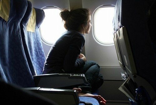 девушка в салоне самолета смотрит в иллюминатор