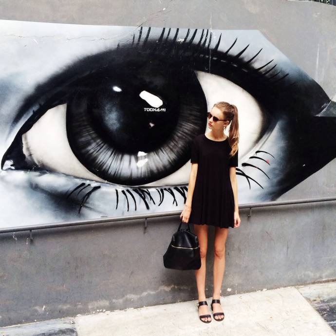 Девушка у стены с нарисованным глазом
