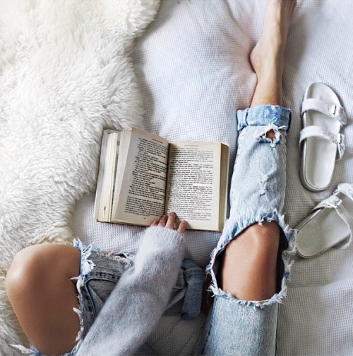 Девушка в рваных джинсах читает книгу