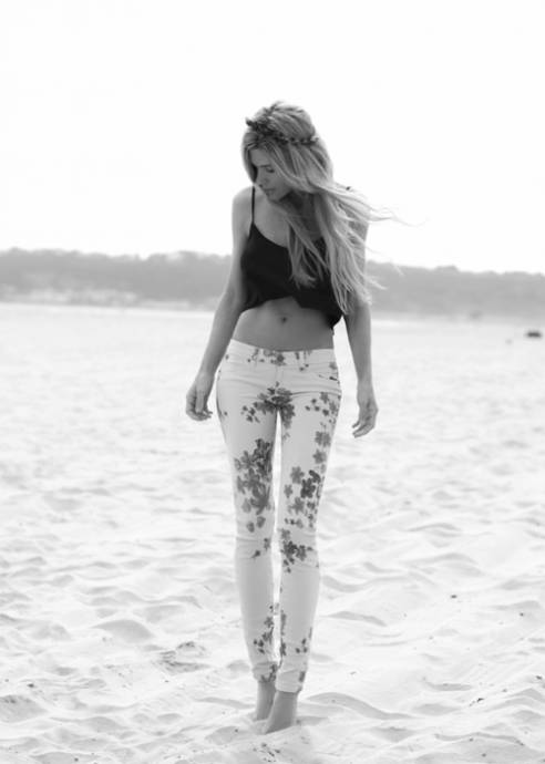 Длинноногая блондинка в брючках с цветами на песке