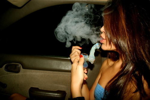 девушка в автомобиле выдувает дым сигареты
