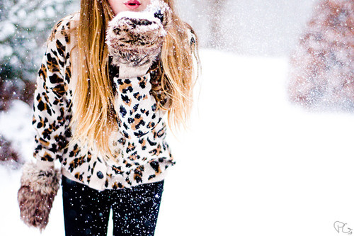 Девушка в леопардовой шубке сдувает снежинки