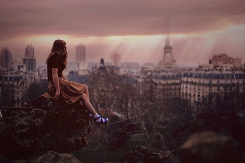 Девушка сидит на крыше и смотрит на город