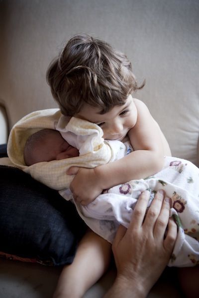 Мальчик держит на руках своего новорожденного брат