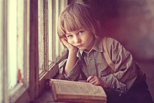 Серьезный мальчик читает книгу у окна
