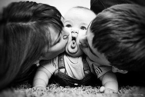 мама с папой целуют пухлощекого ребеночка