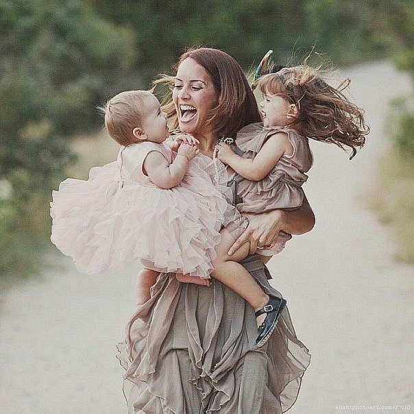 счастливая мама держит на руках двоих  детей