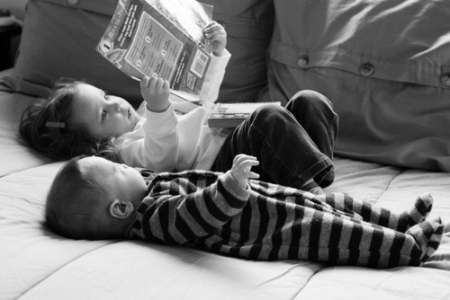 Сестренка с братишкой читают лёжа журнал