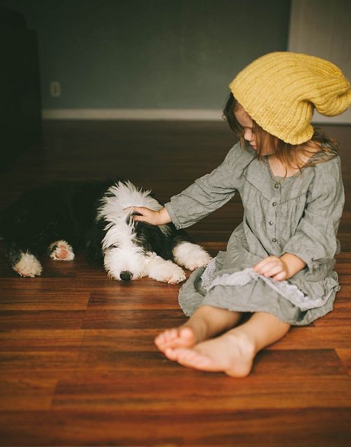Девочка в жёлтой шапке гладит собаку
