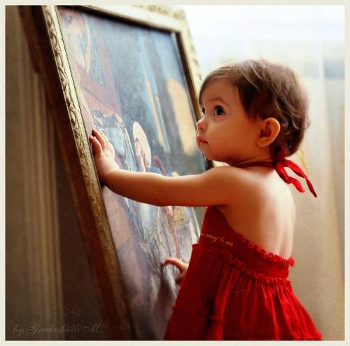 маленькая девочка в красном платье у картины
