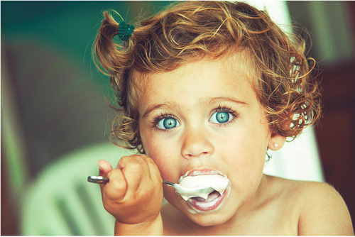 голубоглазая девочка с ложкой йогурта
