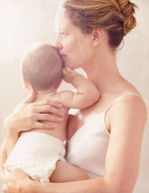 Мама держит малыша на руках и целует его голову
