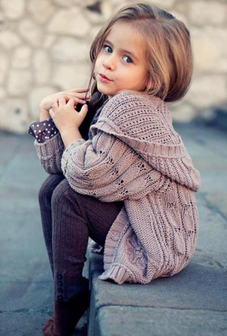 Модная девчушка в вязаной кофте с капюшоном