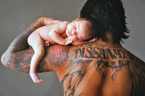 Папа с татуировками на спине с малышом на плече