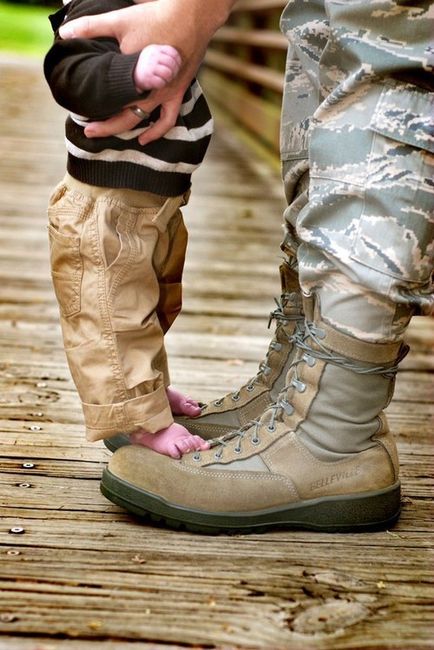 малыш стоит на ботинках солдата в камуфляже