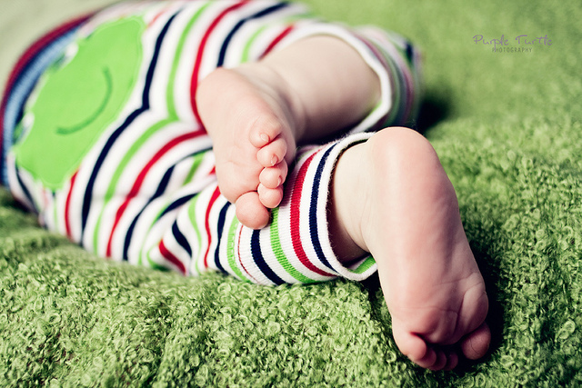 Ножки ребенка в полосатых ползунках на ковре