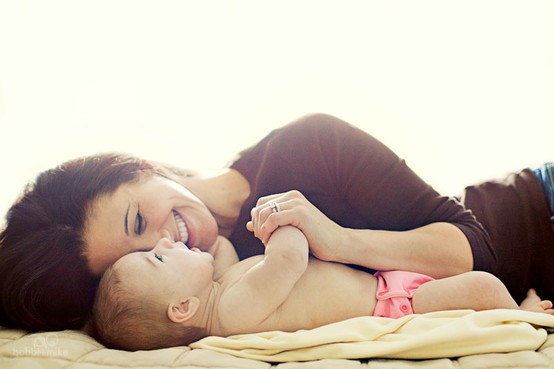 Счастливая мама смеются на кровати со свои малышом