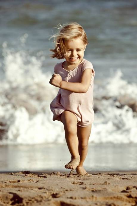 Убегающая от волн моря, смеющаяся девочка