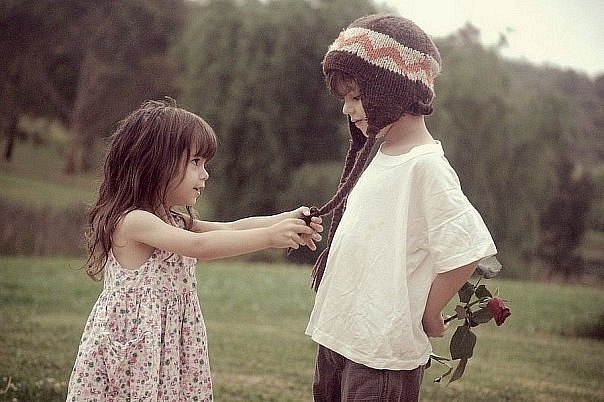 мальчик прячет розу за спиной и девочка
