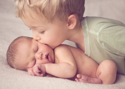 мальчик целует своего спящего новорожденного брата