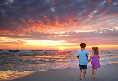 Мальчик с девочкой идут за ручку по берегу моря