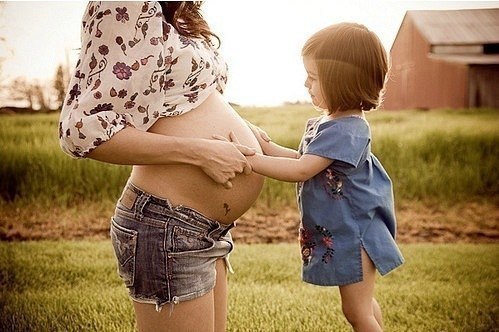 девчушка обнимает живот беременной мамы
