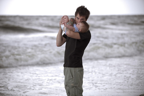 Молодой папа целует своего малыша у моря