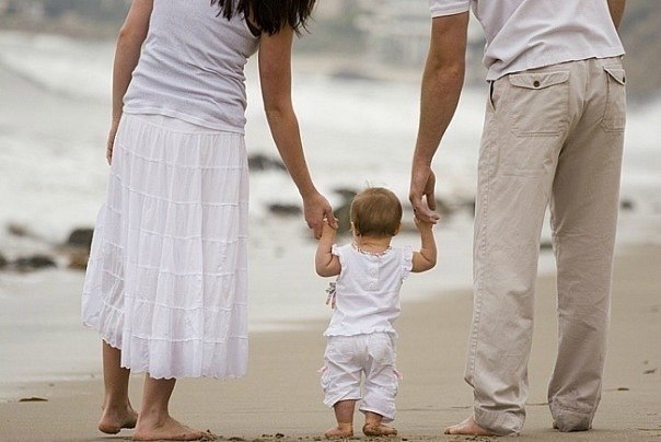 мама с папой держат ребенка за руки по обе стороны