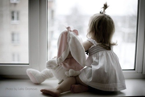 малышка сидит на подоконнике с плюшевым зайцем