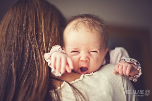 Смешная зевающая малышка из-за плеча мамы